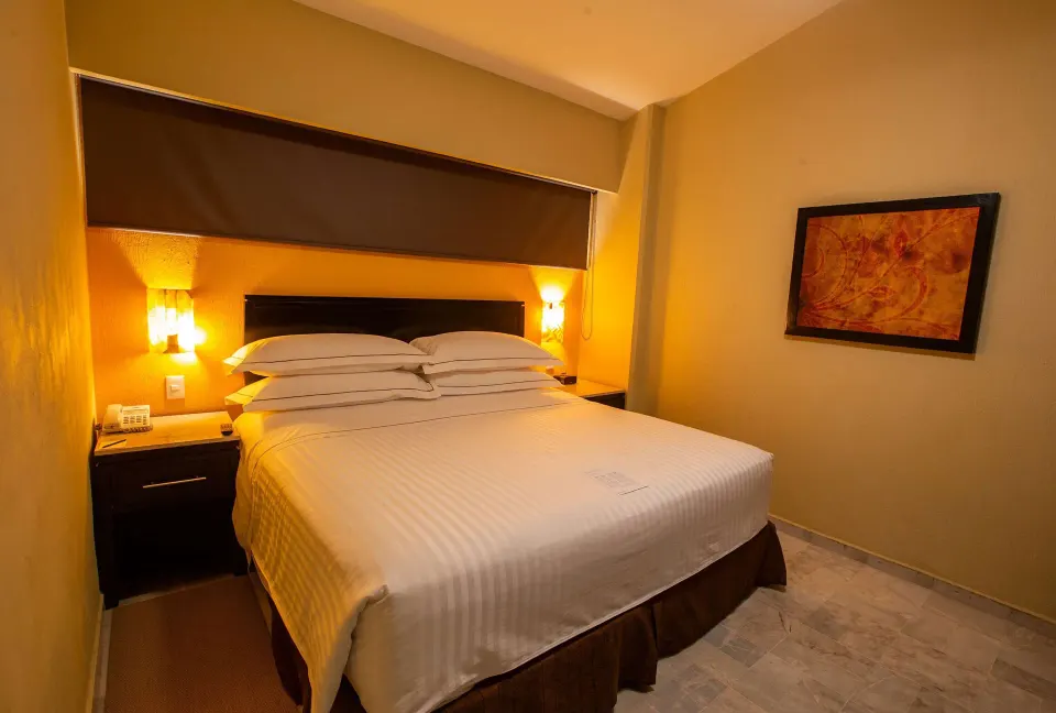 Family Room king bed with bedside lamps and wall art at Barceló Puerto Vallarta.