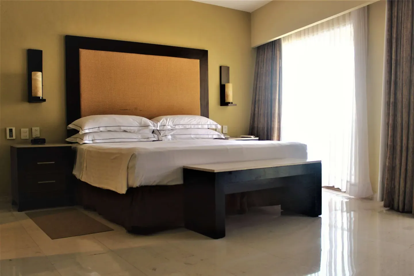 Grand Master Suite king bed beside bright balcony curtains at Barceló Puerto Vallarta.