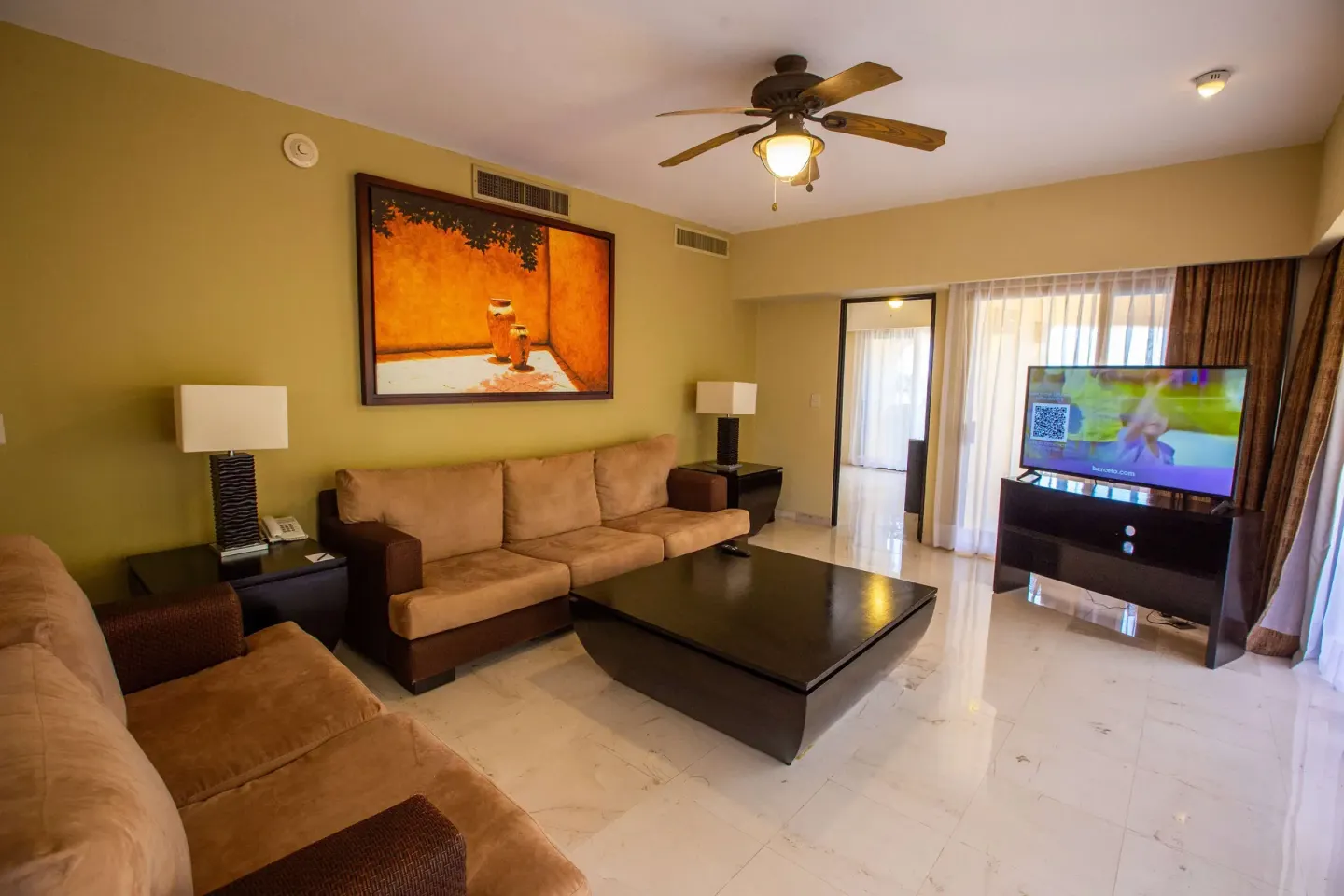 Master Suite living room with sofas, coffee table and TV at Barceló Puerto Vallarta.