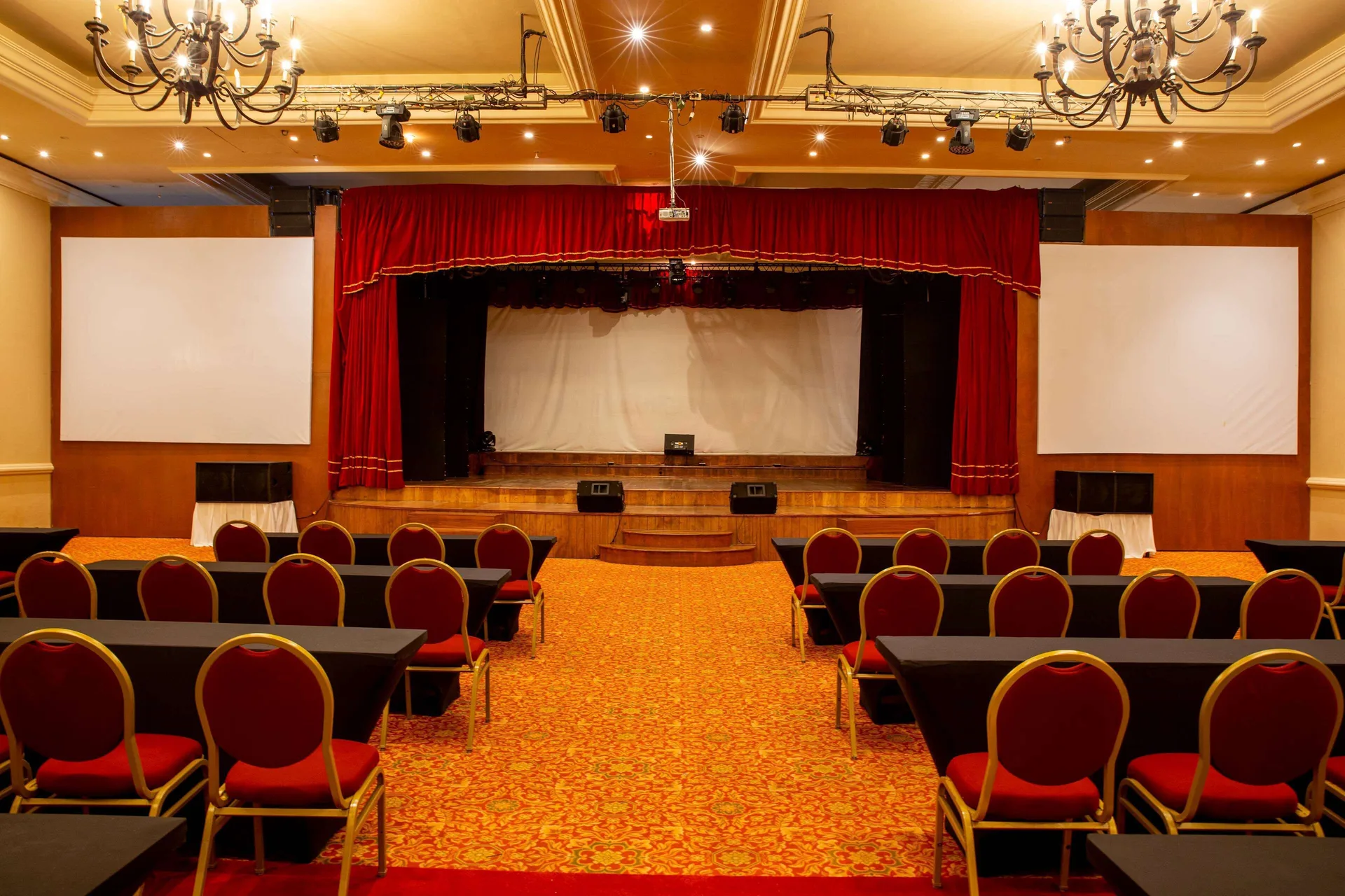 Conference room with stage, red curtain, screens, and classroom seating at Barceló Puerto Vallarta.