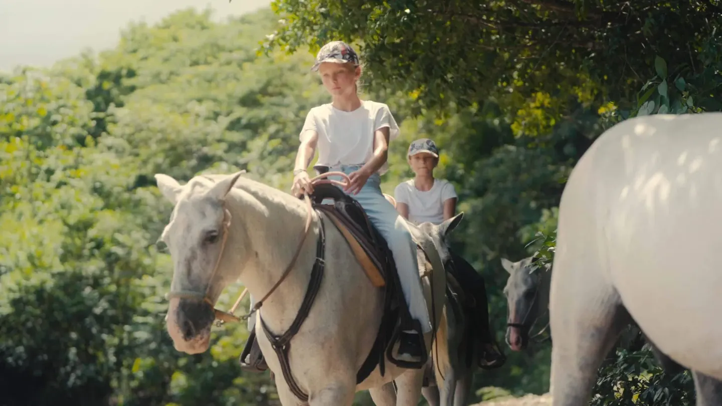 Children riding horses on a shaded trail at Barceló Tambor.