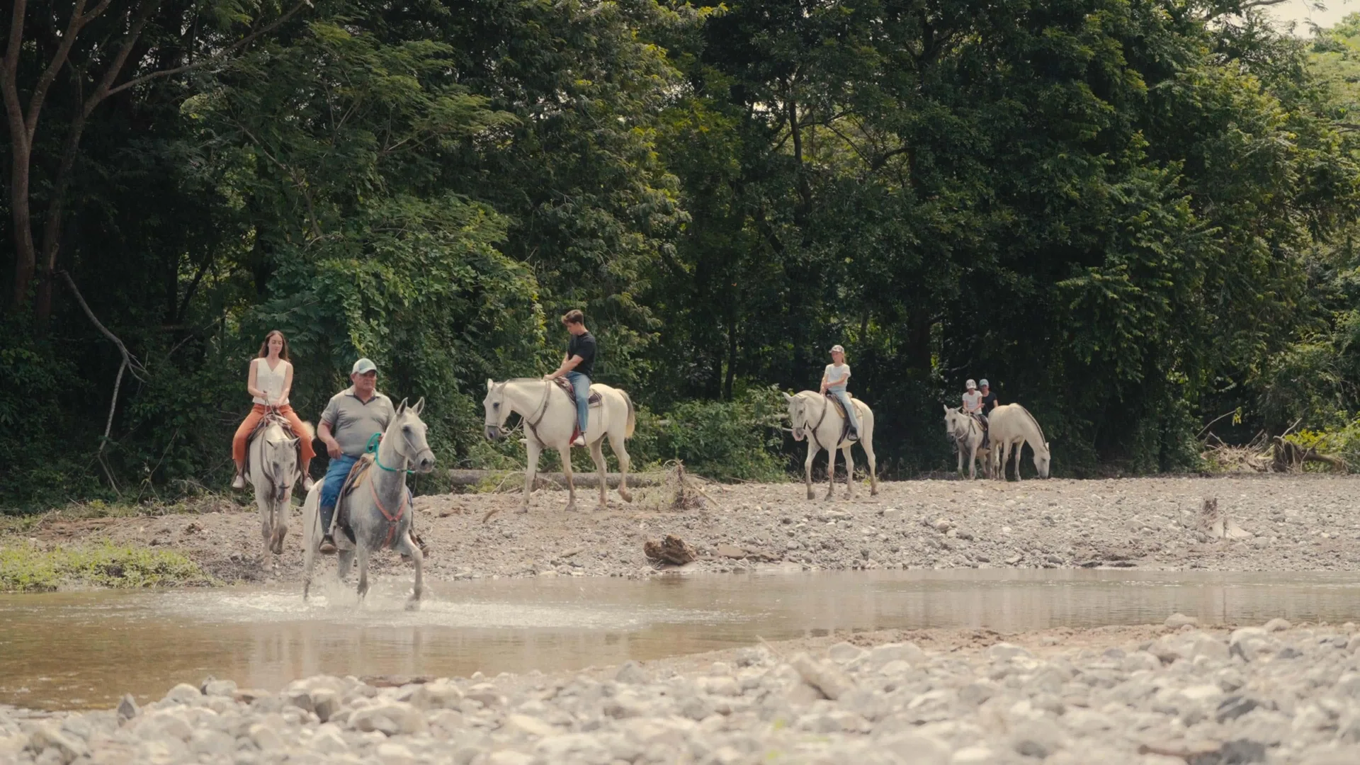 Group horseback ride crossing a shallow rocky stream at Barceló Tambor.