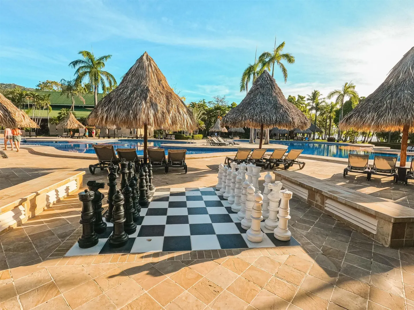 Pool terrace with thatched shade palapas and a giant chessboard at Barceló Tambor.
