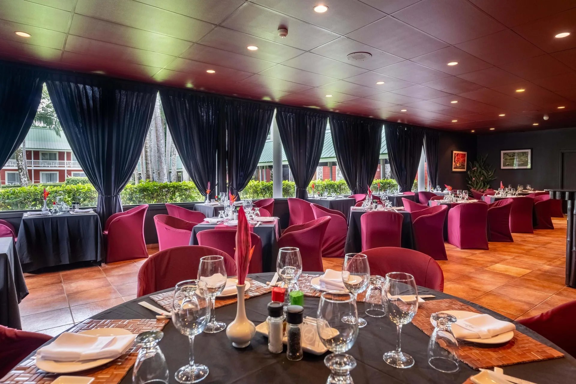 Dining room with red chairs, black linens, and curtained windows at Barceló Tambor.