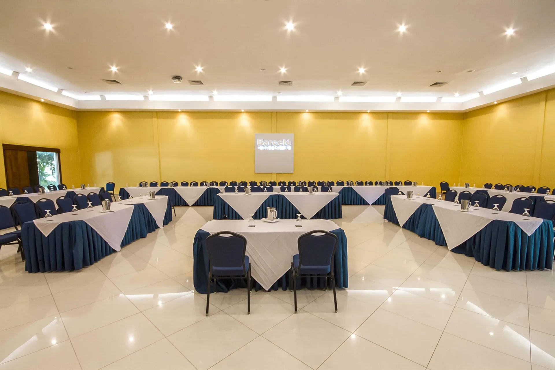 U-shaped meeting tables in a yellow-walled event room at Barceló Tambor.