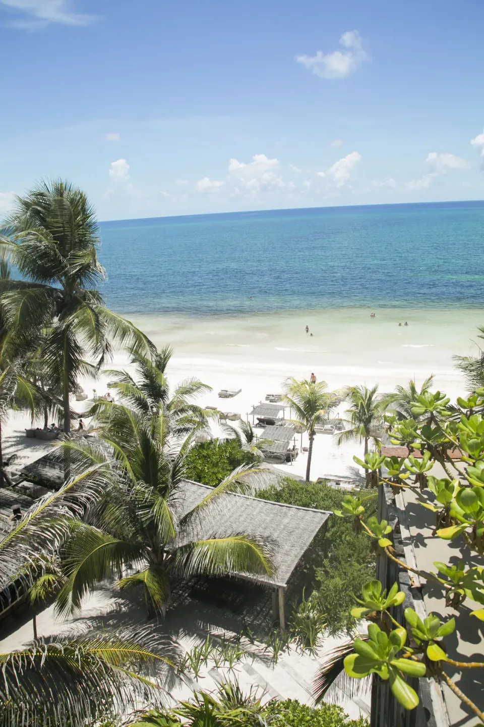 Aerial view of palms, thatched roofs and the turquoise ocean at BE Destination Tulum
