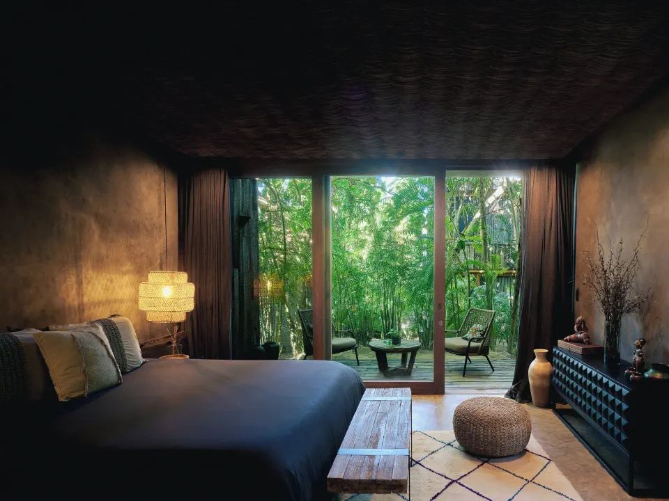 Bedroom with king bed and glass doors opening to jungle terrace at BE Destination Tulum