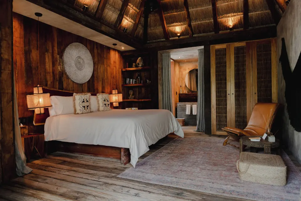 King bedroom with open doorway to bathroom and rustic furnishings at BE Destination Tulum
