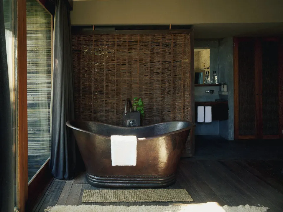 Freestanding bronze bathtub on wooden deck at BE Destination Tulum