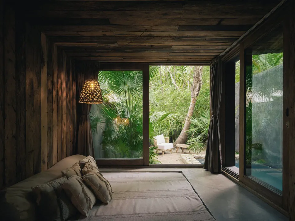 Low seating daybed facing glass doors and tropical garden at BE Destination Tulum