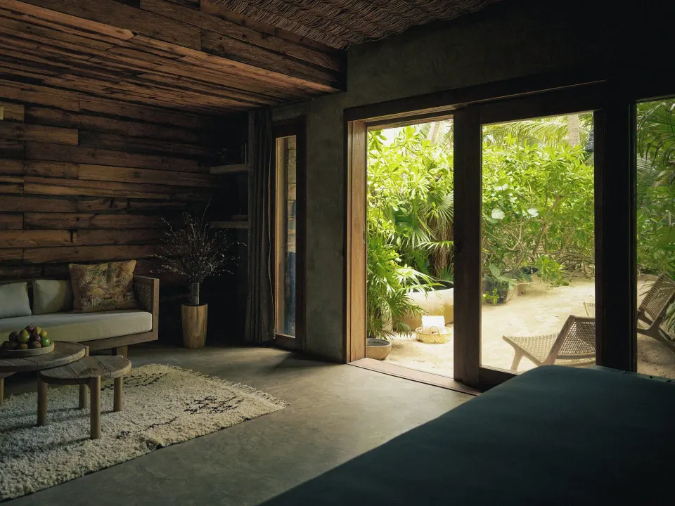Room interior with seating area and sliding doors opening to a private garden at BE Destination Tulum