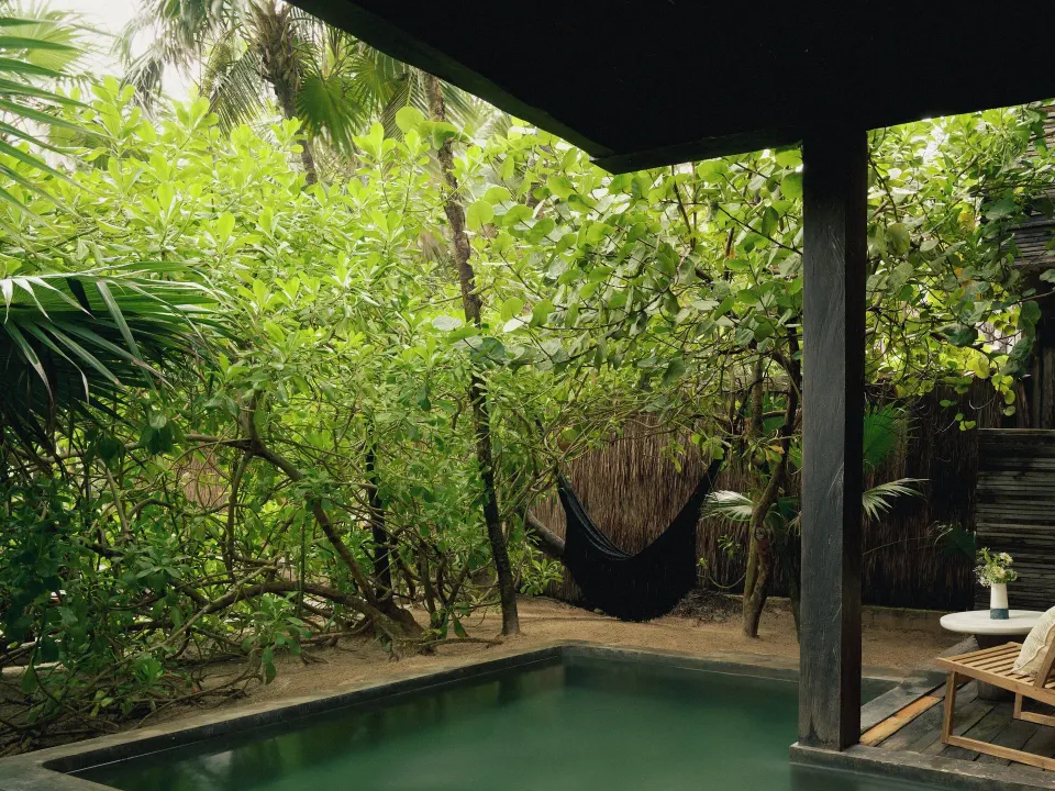 Covered plunge pool with sun lounger and hammock in lush garden at BE Destination Tulum