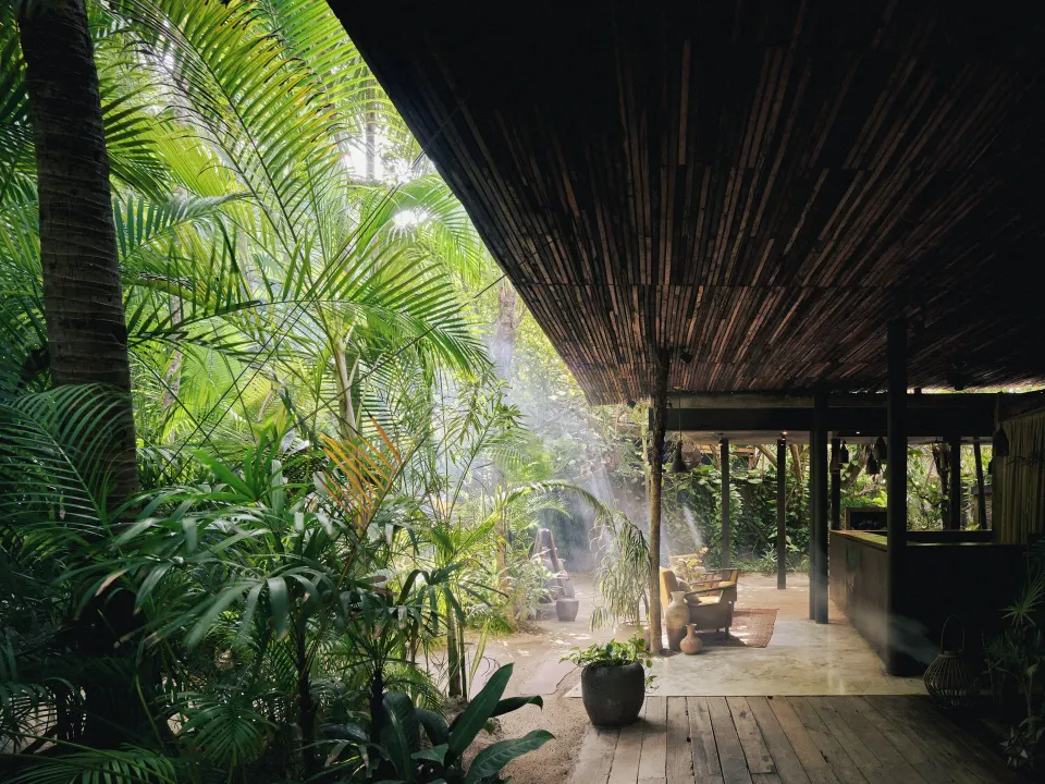 Wooden canopy walkway opening to lush garden and seating at BE Destination Tulum
