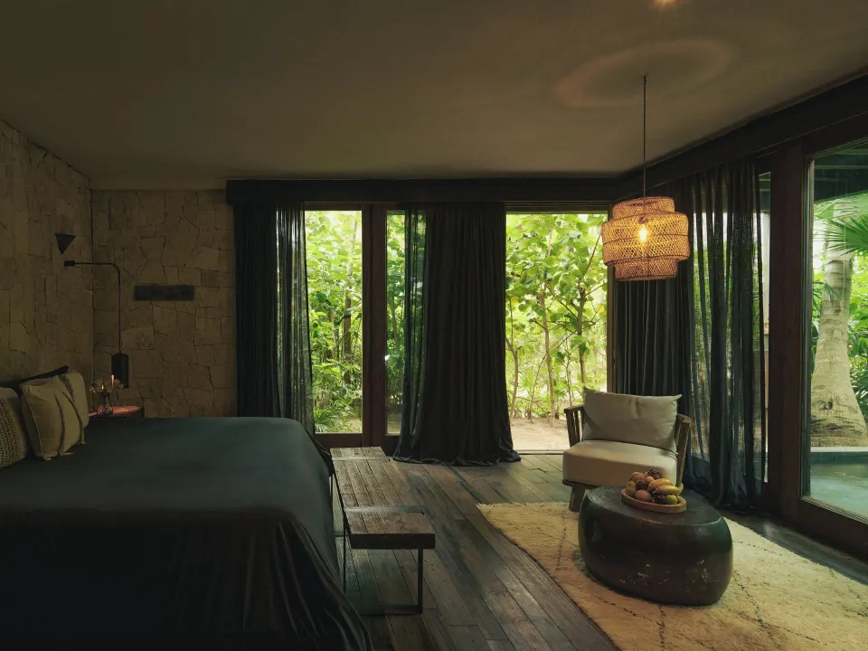 Spacious guest suite with king bed and sliding glass doors to jungle at BE Destination Tulum