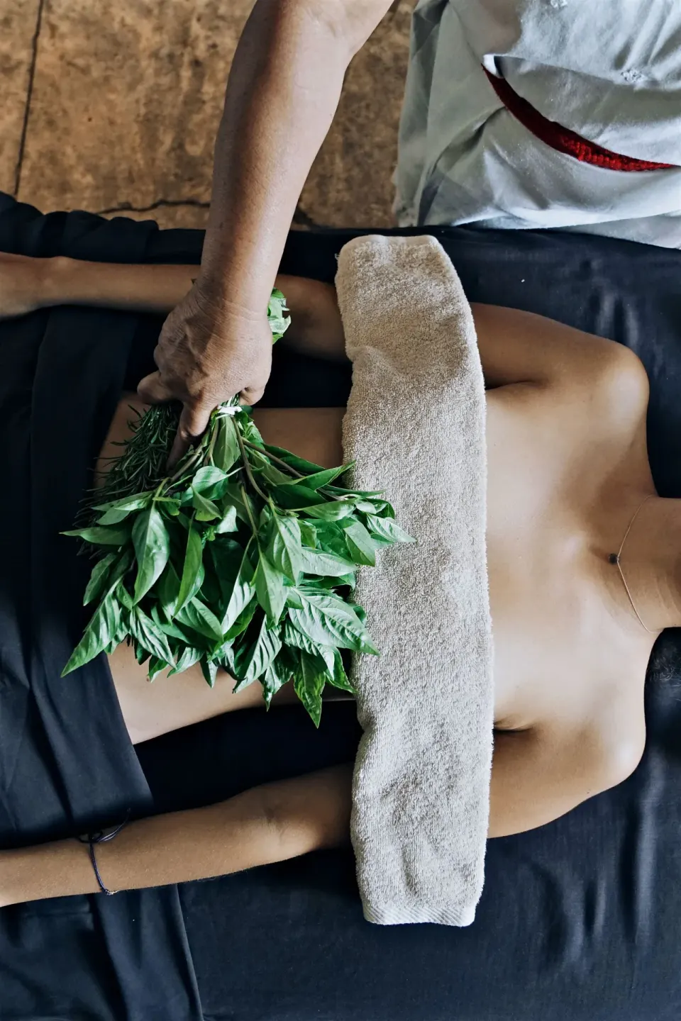 Therapist applying fresh herbal poultice during massage at BE Destination Tulum