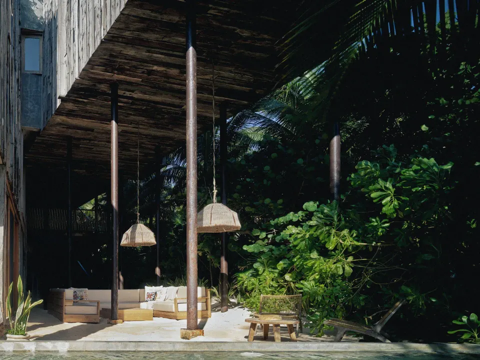 Shaded open-air lounge with sofas and hanging lamps at BE Destination Tulum