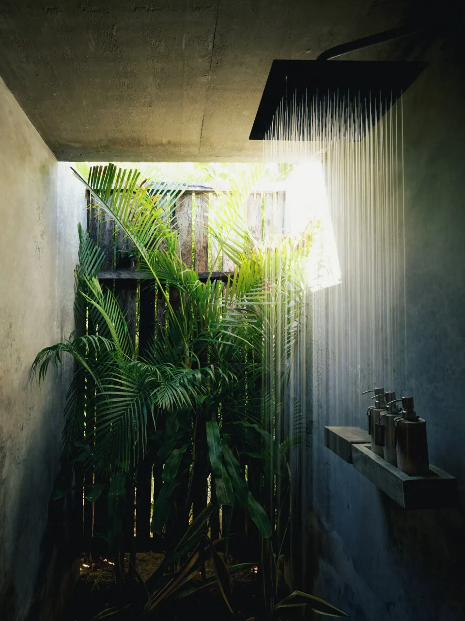 Outdoor rain shower framed by tropical foliage at BE Destination Tulum