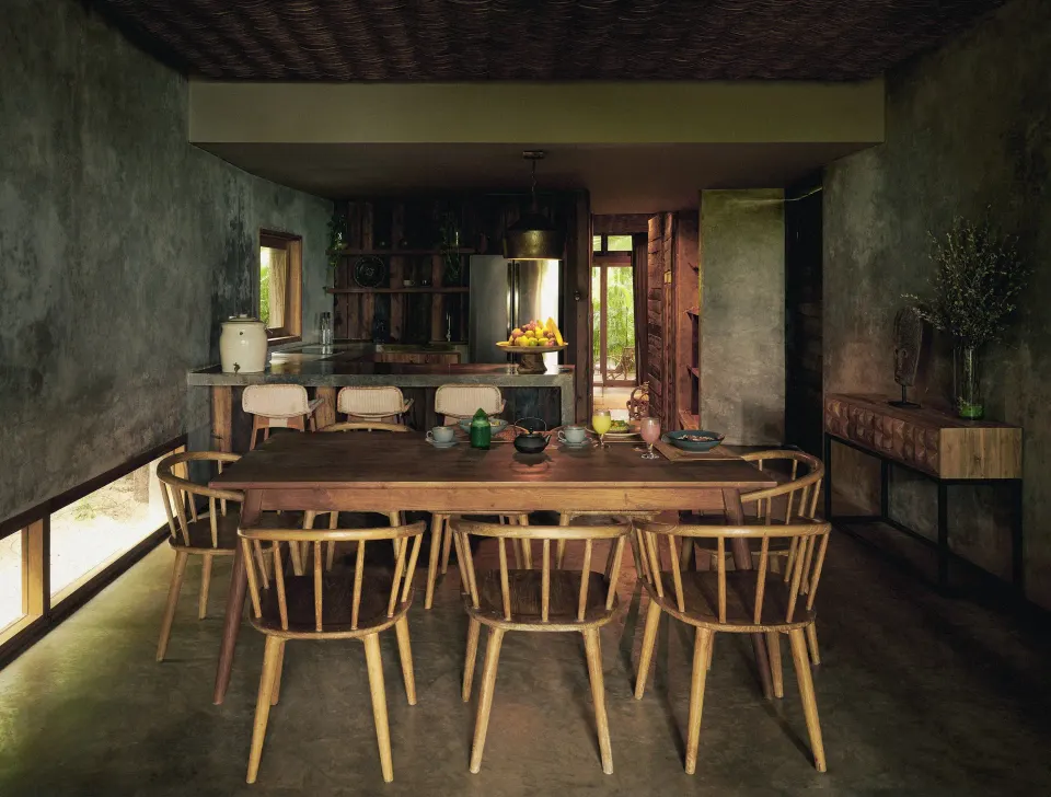 Long wooden dining table and chairs in a rustic dining room at BE Destination Tulum