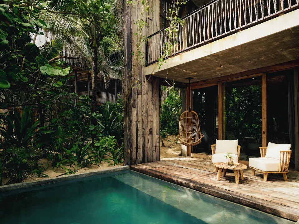 Exterior pool with deck and hanging chair beneath upper balcony at BE Destination Tulum