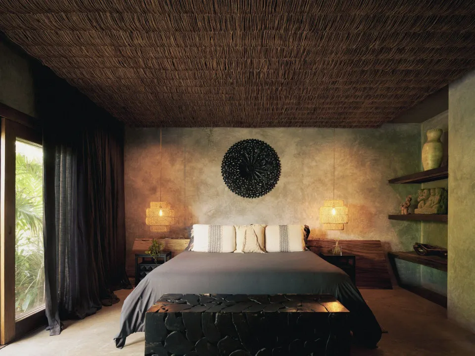 King bed against textured wall with woven ceiling in a guest room at BE Destination Tulum