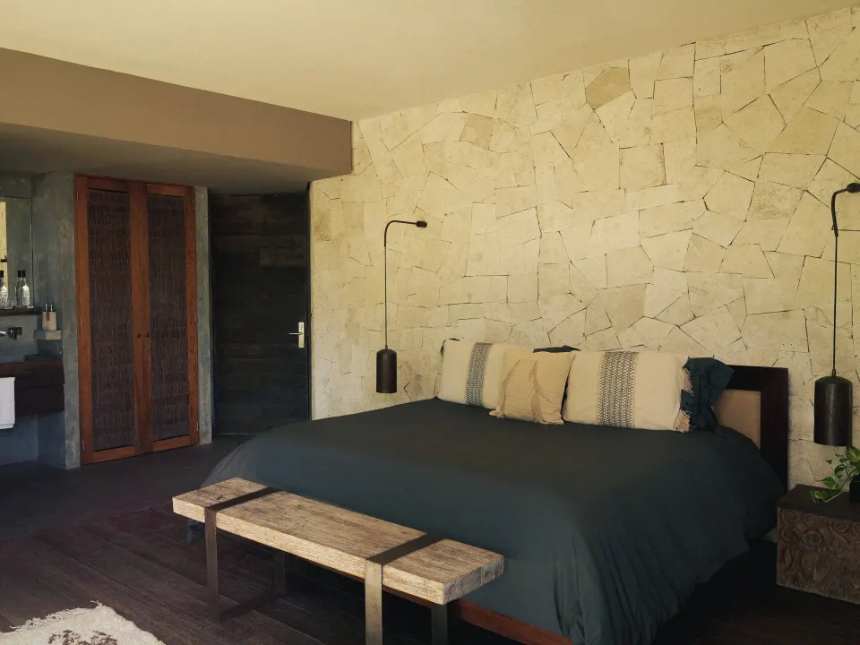 Bright guest room with king bed and stone feature wall at BE Destination Tulum