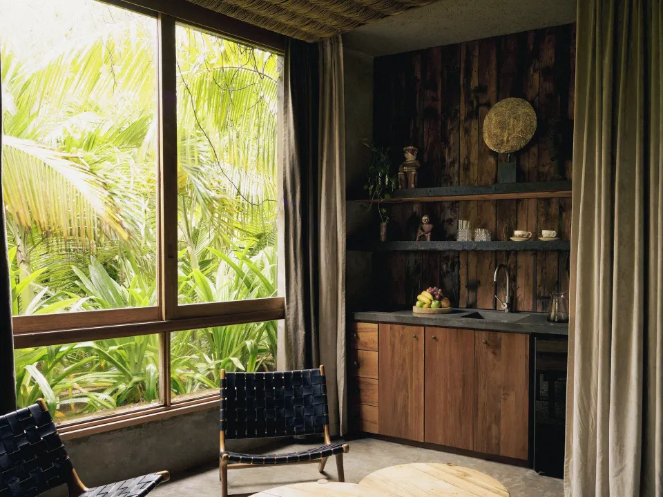 Compact kitchenette and seating area framed by jungle foliage at BE Destination Tulum