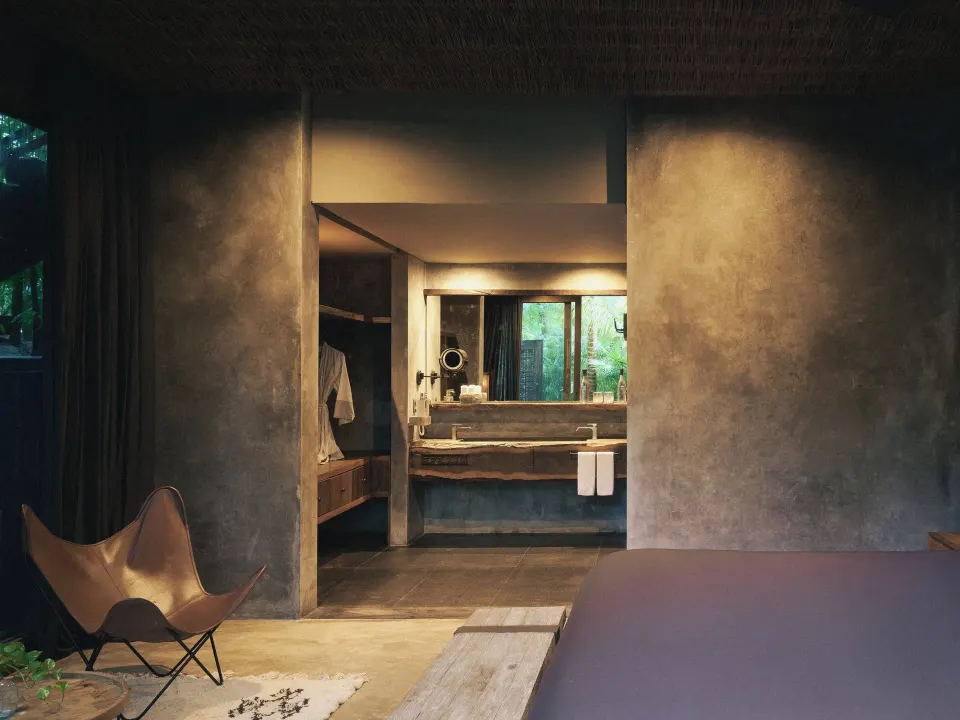 Bedroom view into bathroom with concrete finishes at BE Destination Tulum