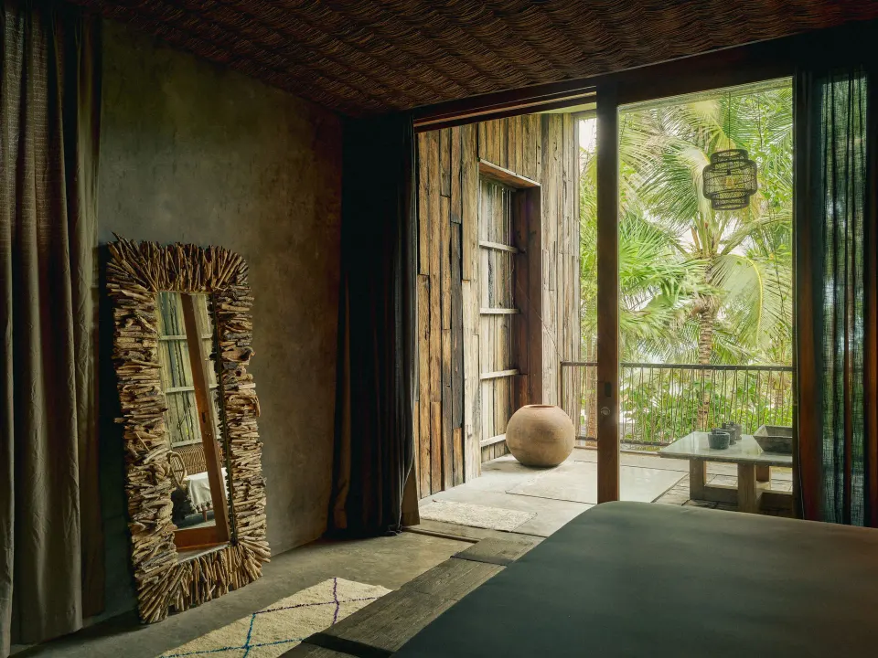 Bedroom opening onto a small balcony with tropical foliage at BE Destination Tulum