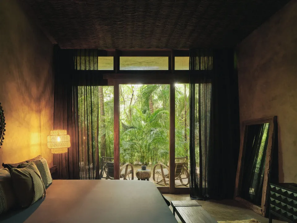 Bedroom opening to a leafy private terrace at BE Destination Tulum