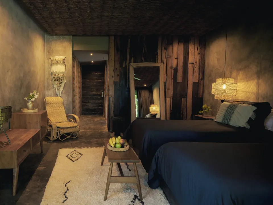 Bedroom with twin beds, wicker chair and rustic decor at BE Destination Tulum