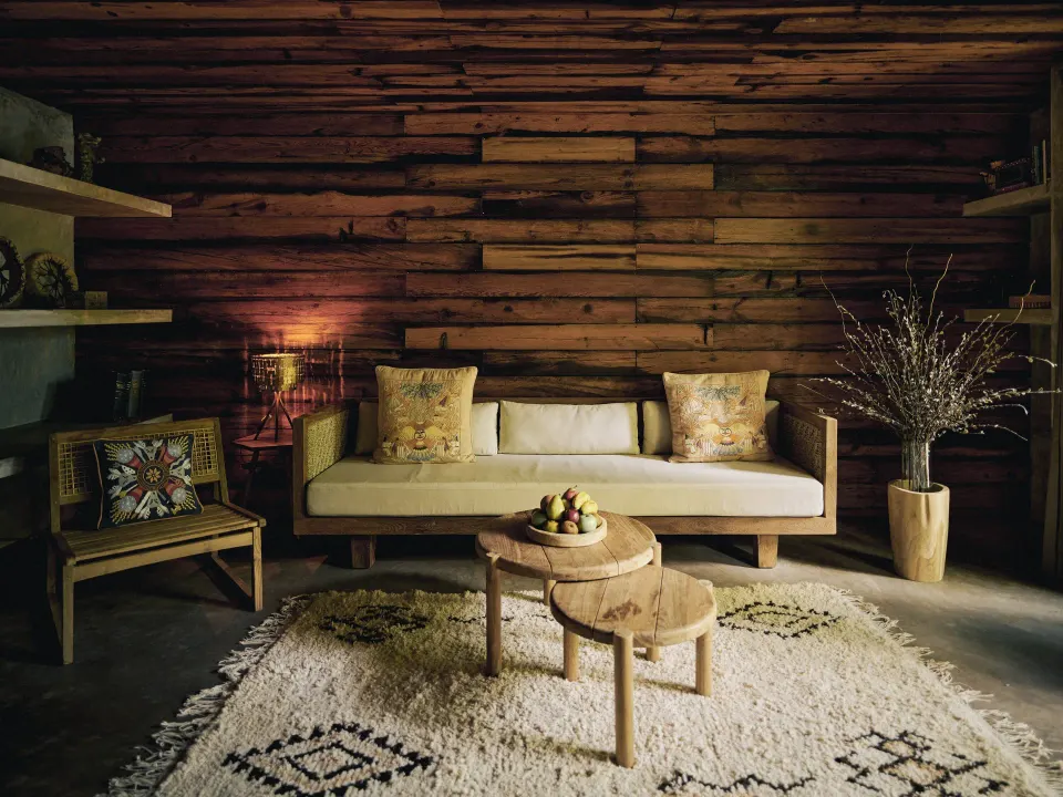 Intimate wood-paneled sitting room with sofa and layered rugs at BE Destination Tulum