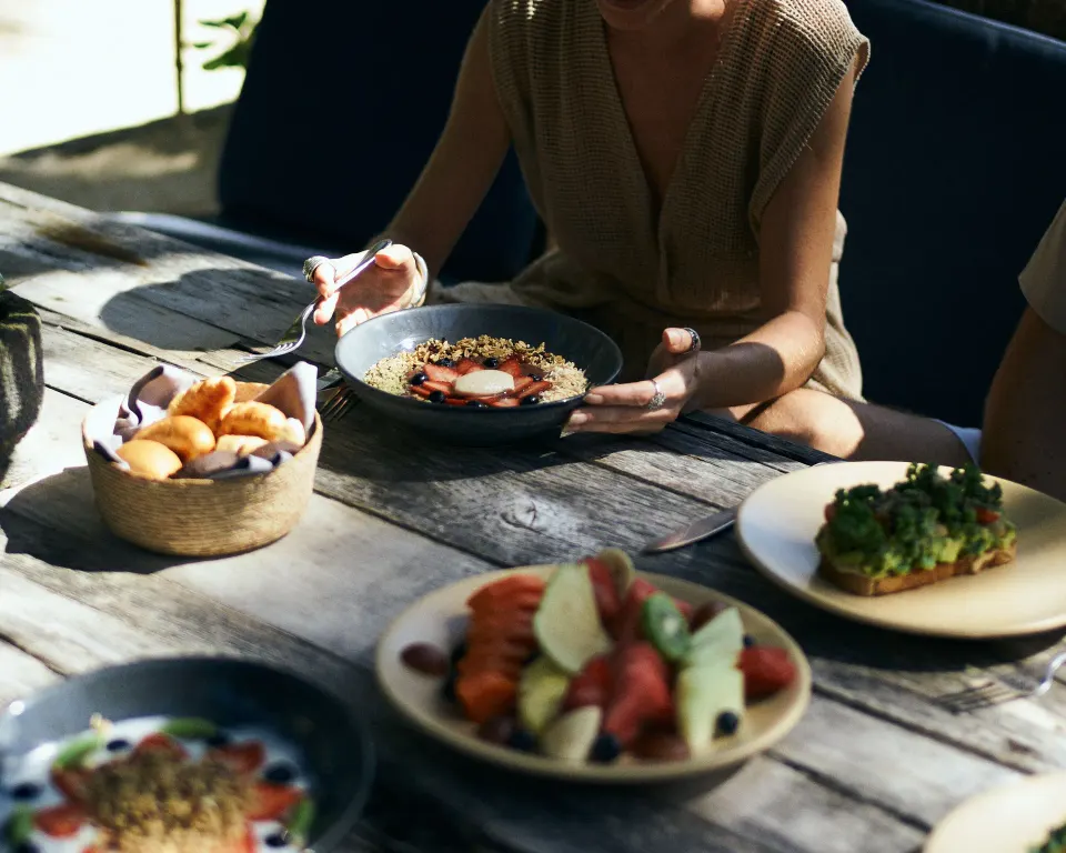 Breakfast spread on a rustic table with guests at BE Destination Tulum