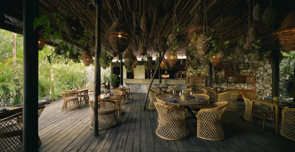 Covered outdoor restaurant dining area with woven chairs at BE Destination Tulum