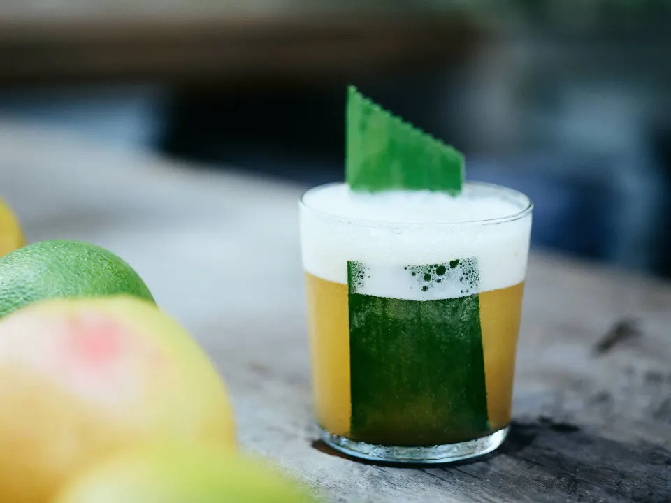 Green cocktail with foam and leaf garnish at BE Destination Tulum