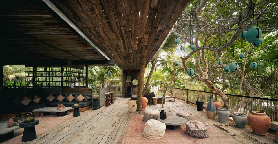 Open-air lounge terrace with seating and potted decor at BE Destination Tulum