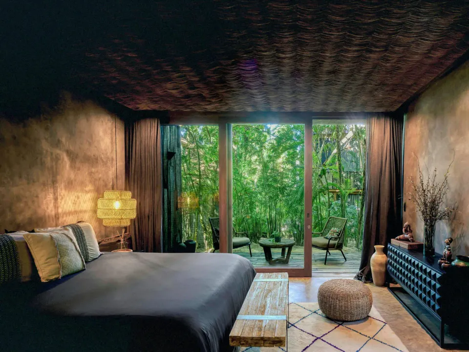 Premier Suite Oceanfront bedroom with sliding glass doors and jungle view at BE Destination Tulum