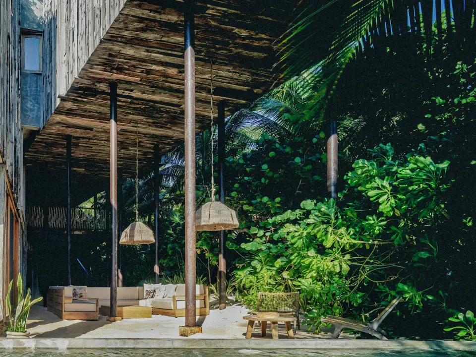 Shaded outdoor lounge under elevated deck surrounded by tropical foliage at BE Destination Tulum