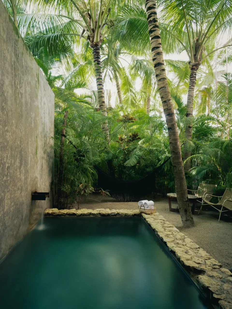 Private plunge pool bordered by palms and stone with lounge area at BE Destination Tulum