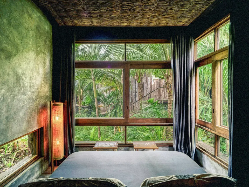Air Suite king bed and large windows looking into lush palms at BE Destination Tulum.