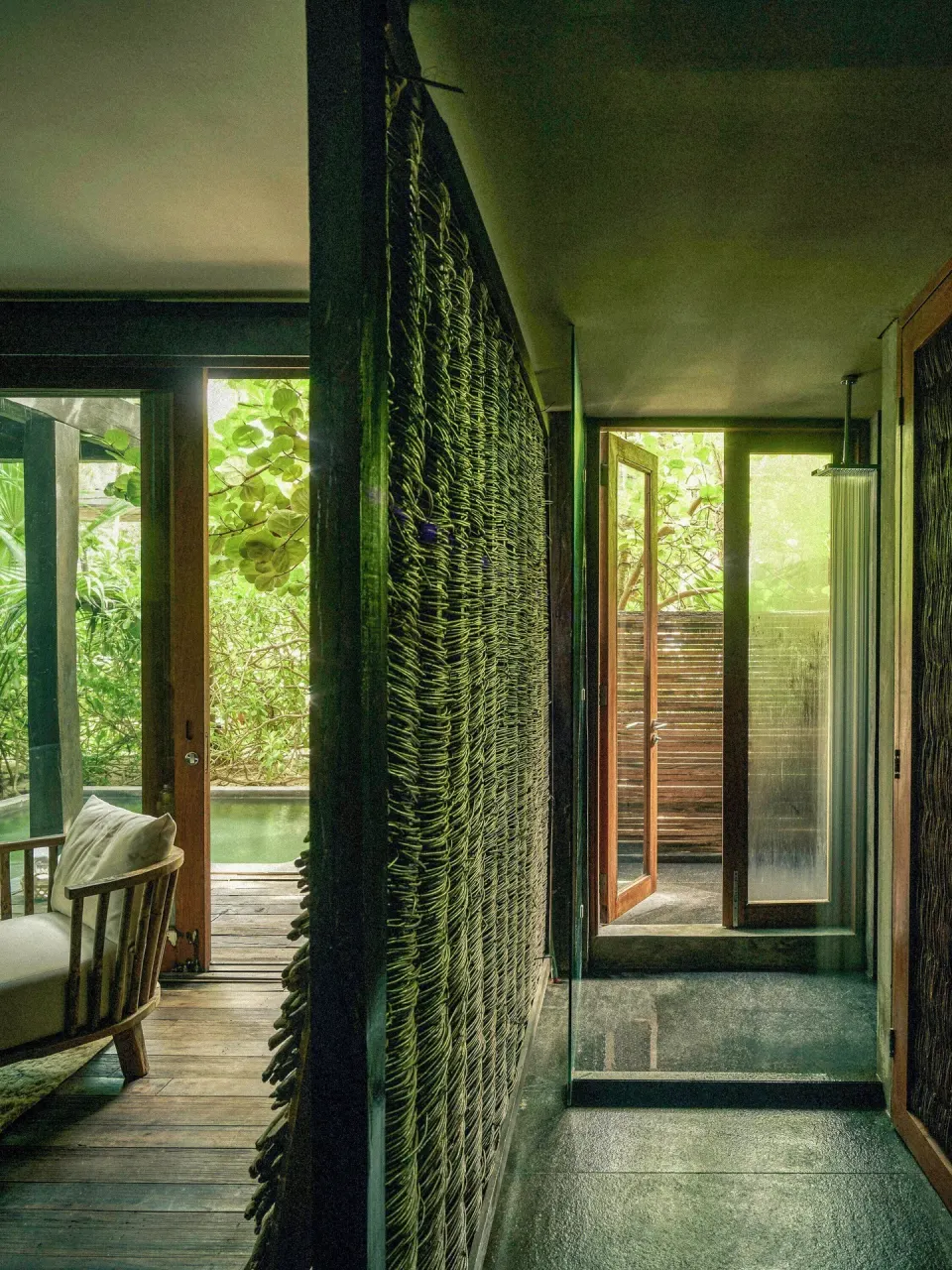 Hallway and seating area with woven divider leading to outdoor shower at BE Destination Tulum