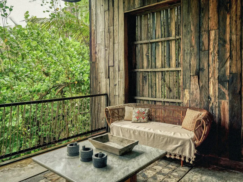 Private terrace seating in an oceanfront suite at BE Destination Tulum with rattan sofa and table