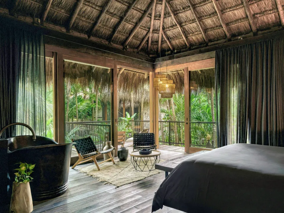 Palm Suite interior showing king bed, seating nook and balcony at BE Destination Tulum