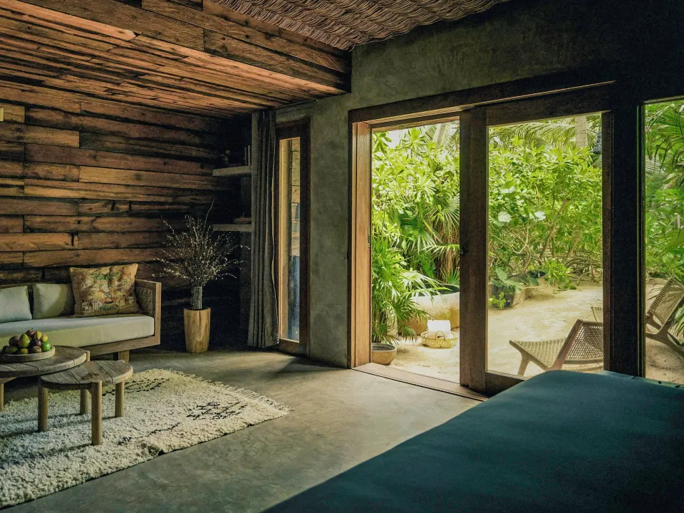 Sea Suite interior showing sofa, floor-to-ceiling doors and garden view at BE Destination Tulum