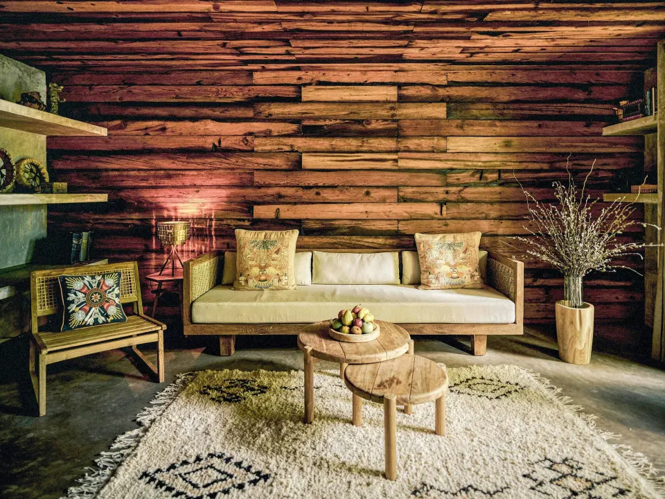 Sea Suite sitting area with sofa, wooden wall and coffee tables at BE Destination Tulum