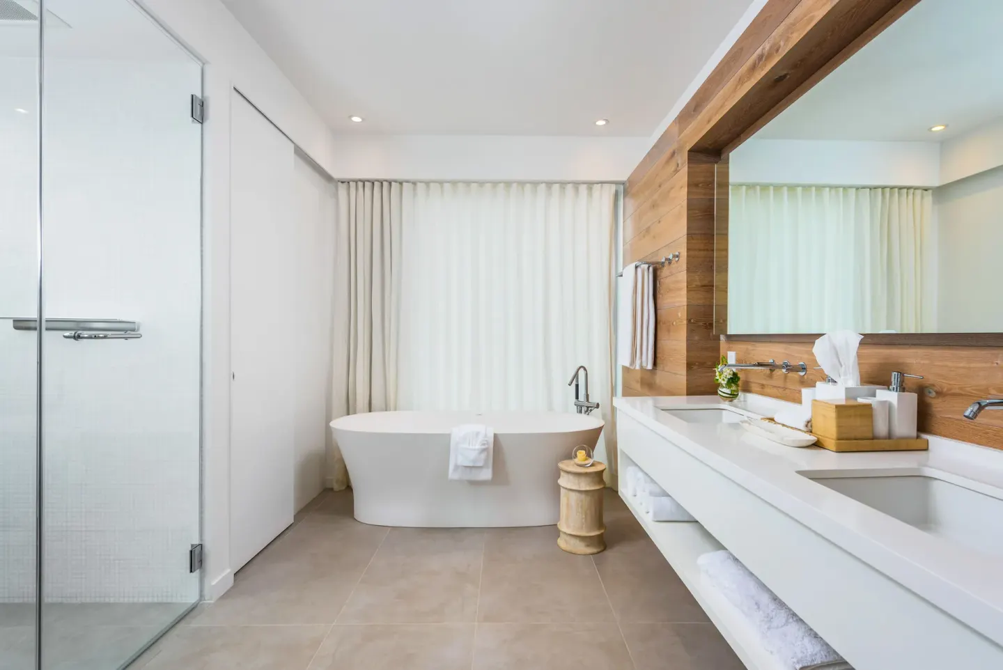 Bathroom with freestanding tub, glass shower, and double vanity at Beach Enclave.