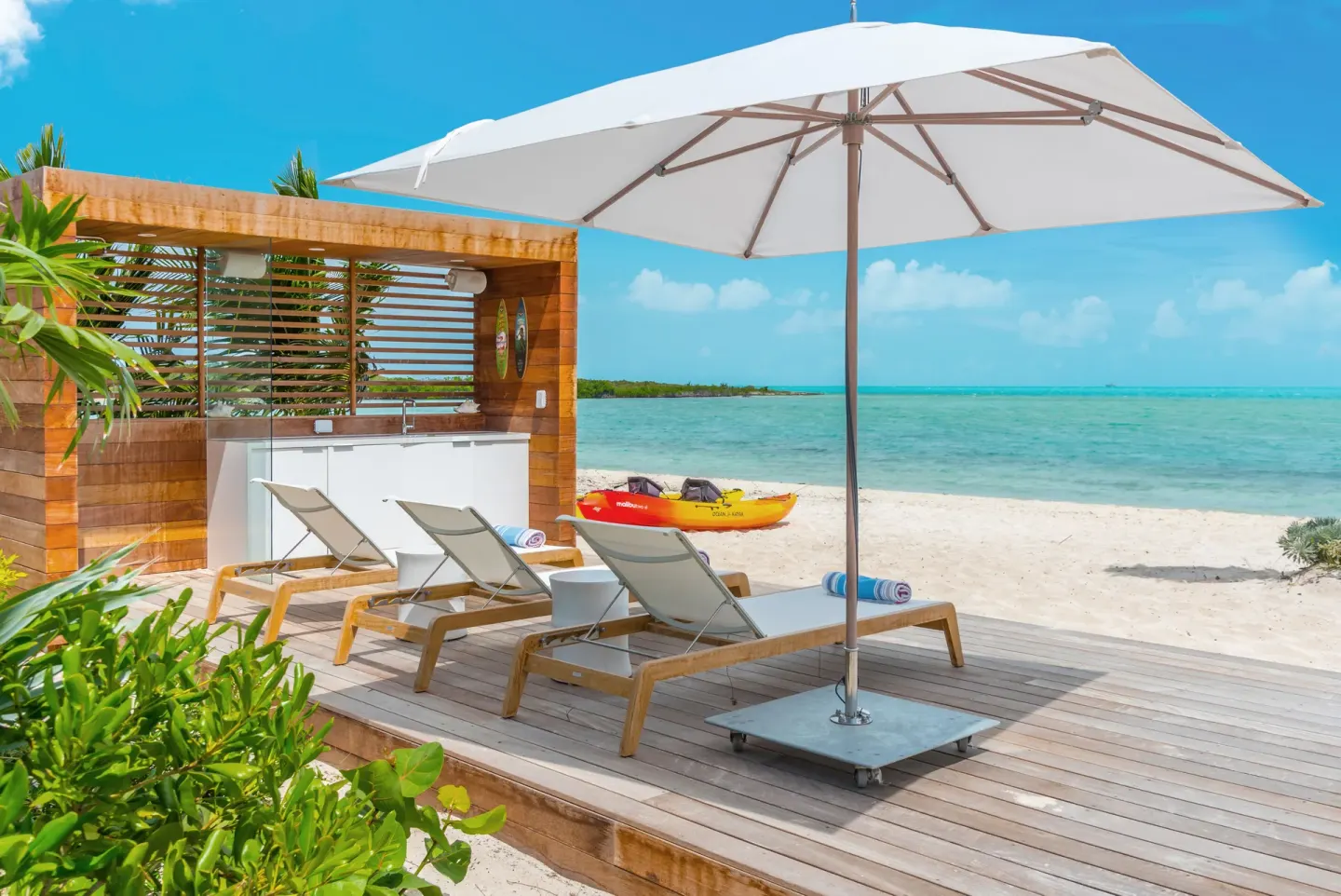 Beach deck with loungers, umbrella, and kayak at Beach Enclave.