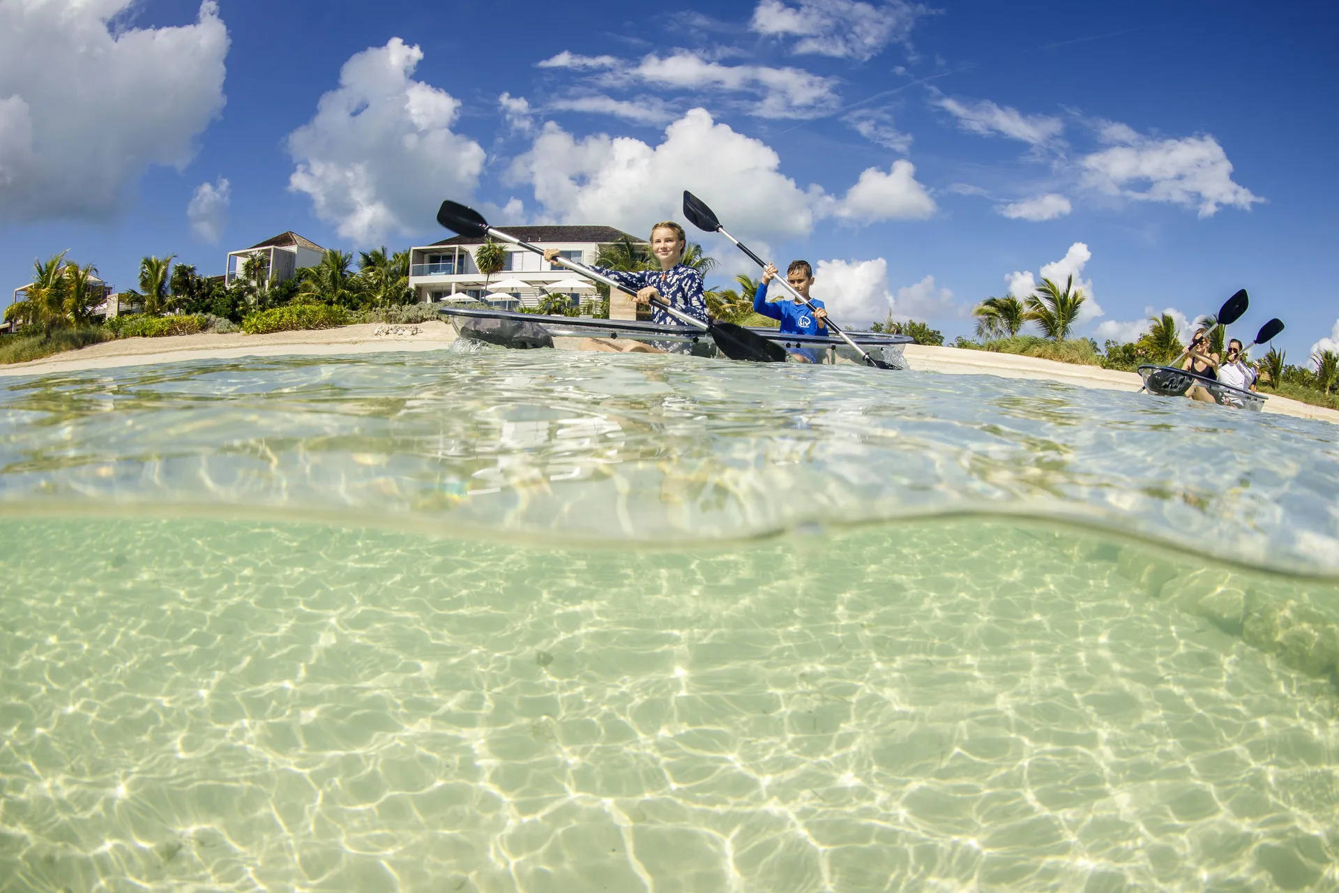 Kayakers paddle in clear shallow water off the beach at Beach Enclave.