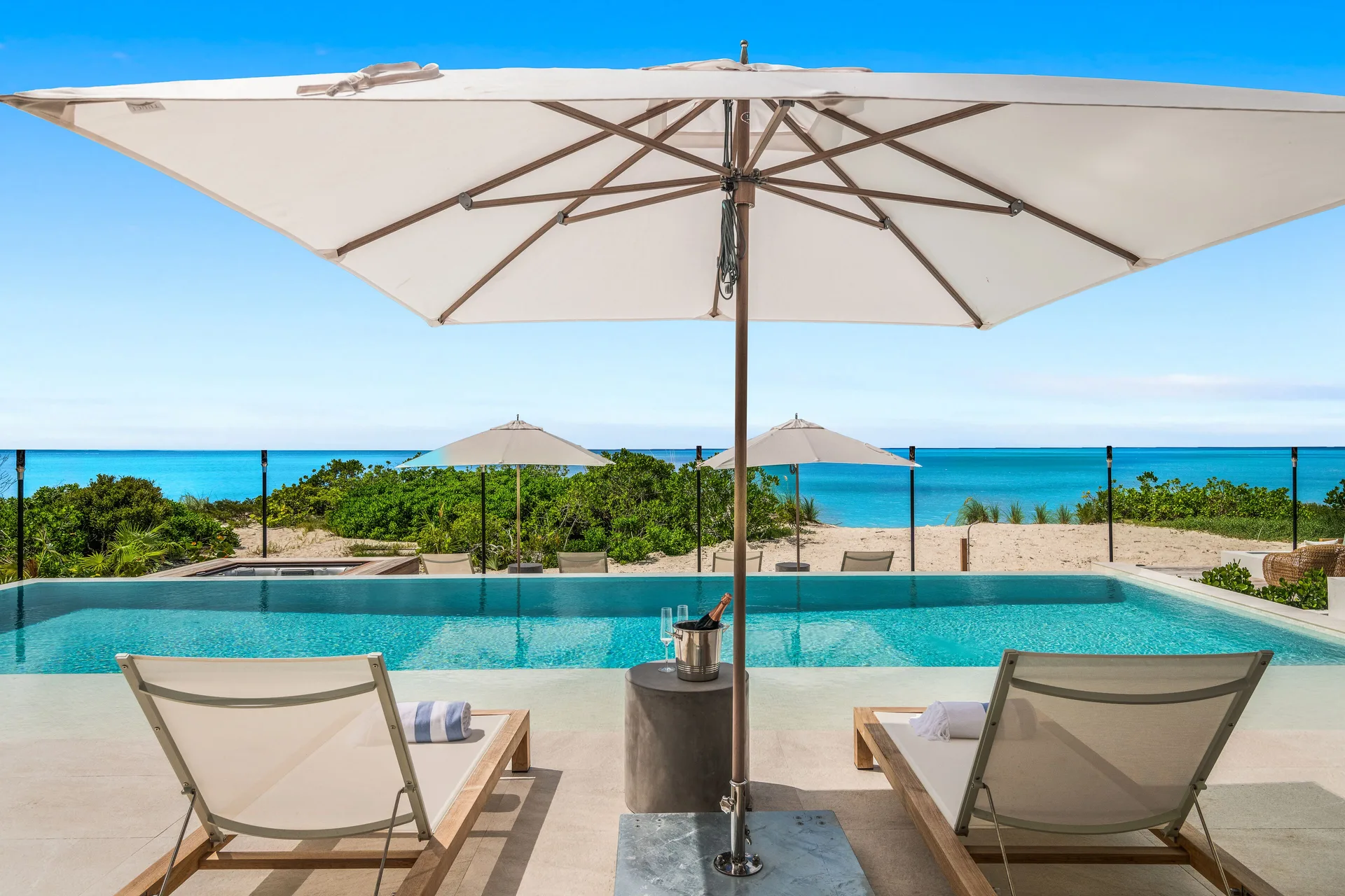 Beachfront infinity pool with loungers and umbrellas at Beach Enclave.