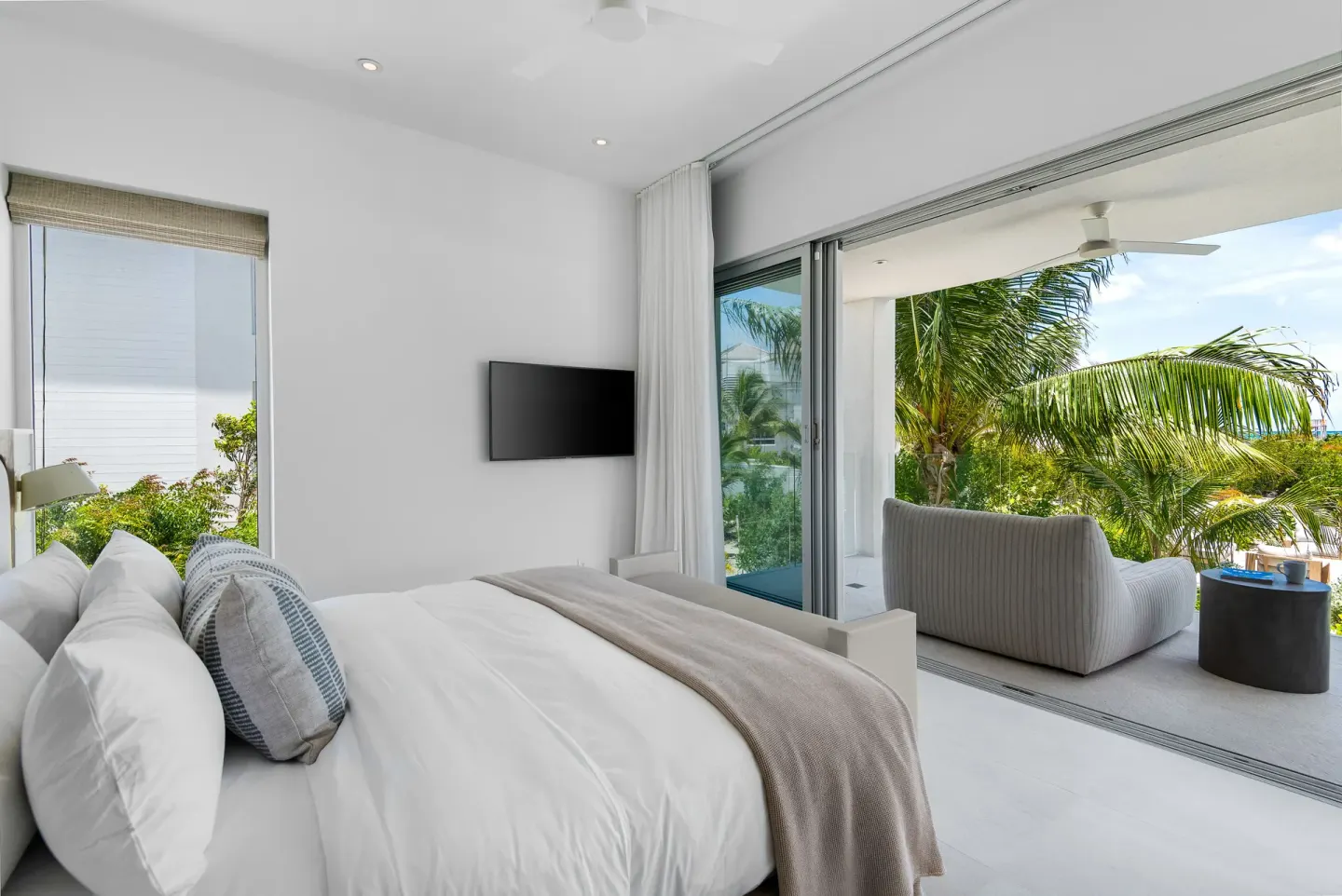 Bedroom with king bed, TV, and balcony seating at Beach Enclave.