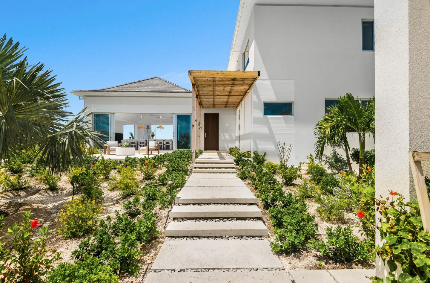 Garden walkway leading to a modern villa entrance at Beach Enclave.